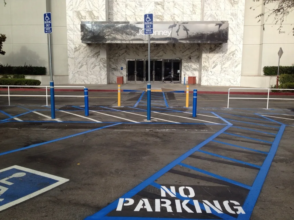 Accessible parking stalls, access aisles, signs, and route markings near a commercial entrance