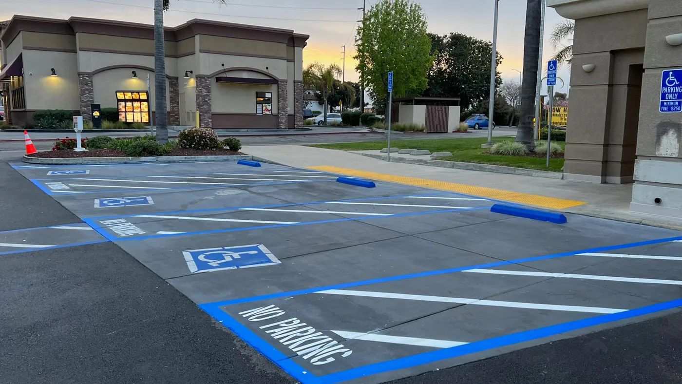 Accessible parking stalls with blue striping, access aisles, signs, and a concrete route connection