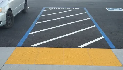 Yellow truncated dome detectable warning surface at the end of an accessible parking access aisle
