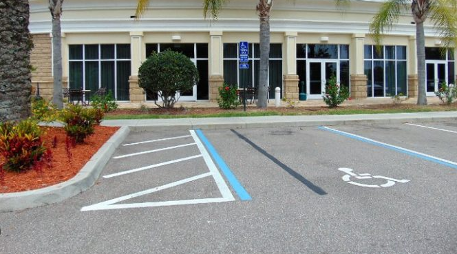 Accessible parking stall with a striped access aisle and posted accessibility sign near a commercial entrance
