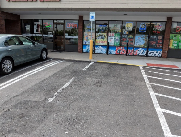 Faded accessible parking stall and access aisle markings outside a storefront