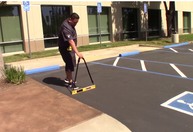Field technician measuring the slope of an accessible parking space with a digital level