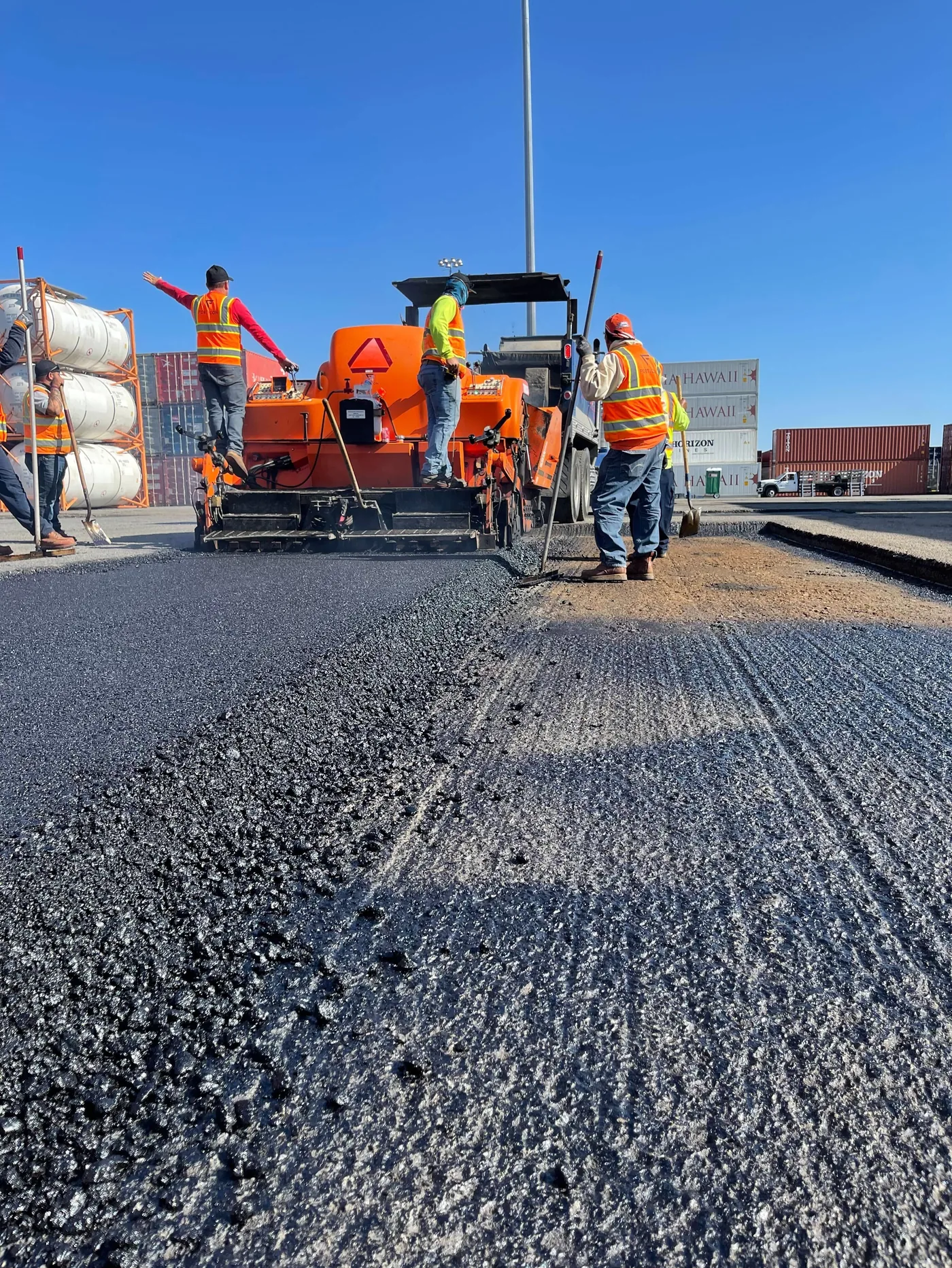 Industrial asphalt paving crew placing hot mix asphalt in a heavy-use work area