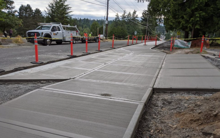 New commercial concrete flatwork and sidewalk panels under construction beside a roadway