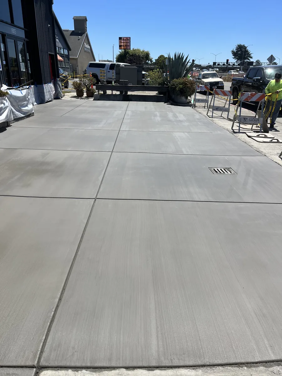 Finished concrete entry flatwork beside a commercial building and parking area