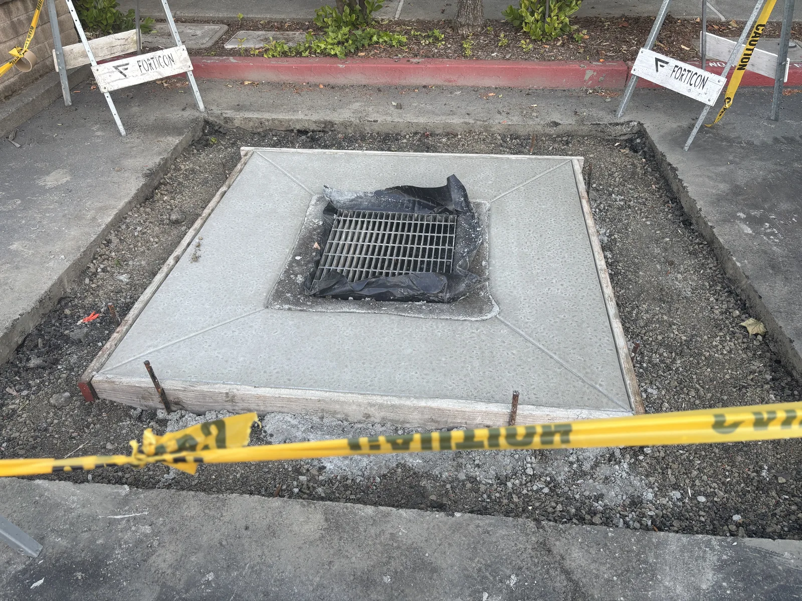 New concrete drain apron formed around a drainage inlet with surrounding pavement prepared for tie-ins