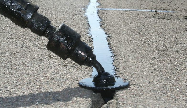Close detail of crack filler being applied into an asphalt crack