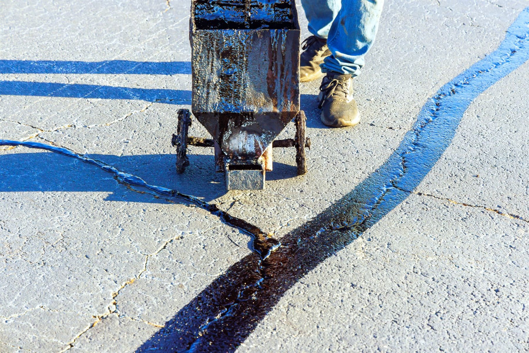 Crack filling machine applying sealant to asphalt pavement