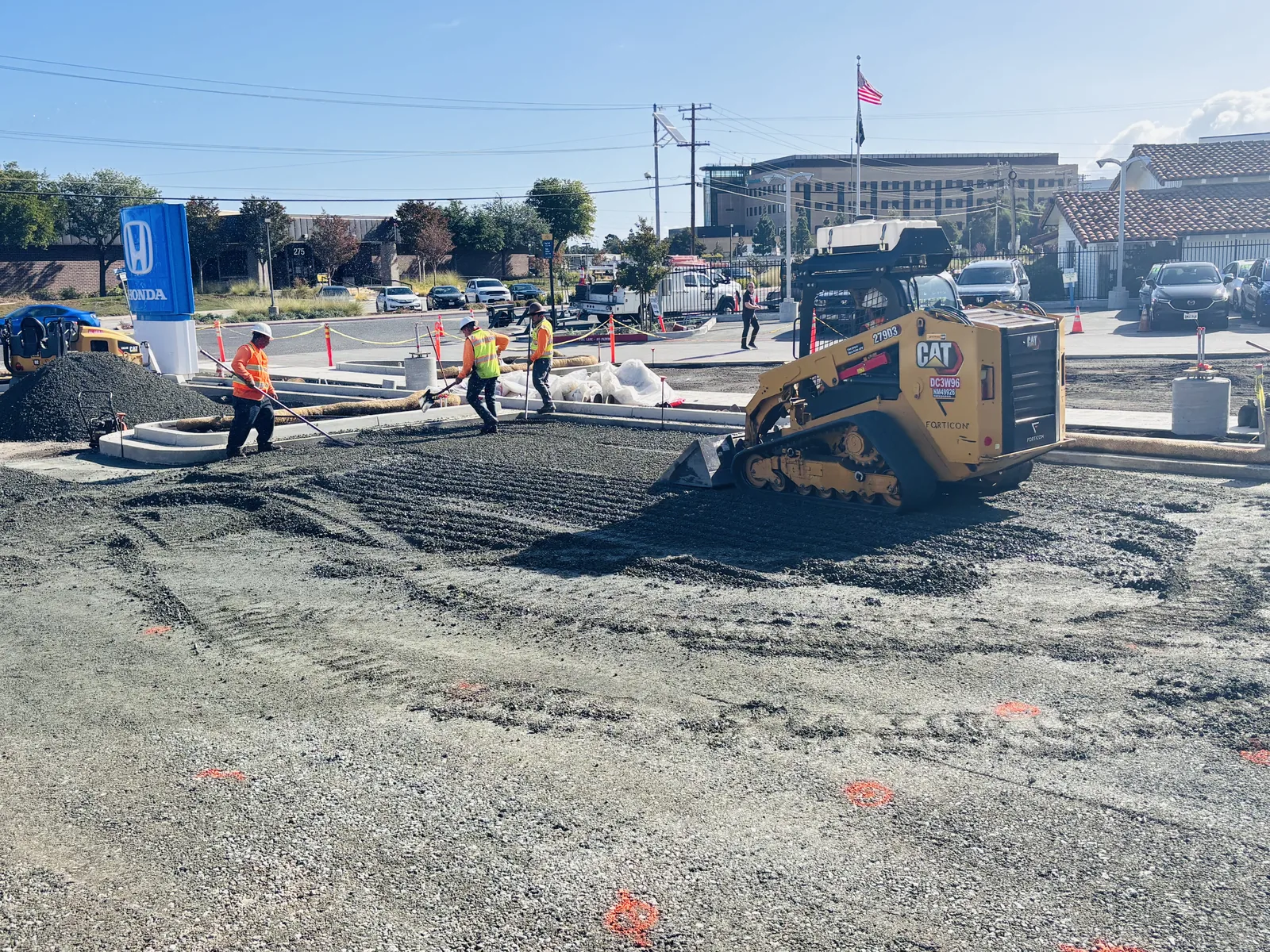 Forticon crew fine grading base rock during parking lot drainage and paving preparation