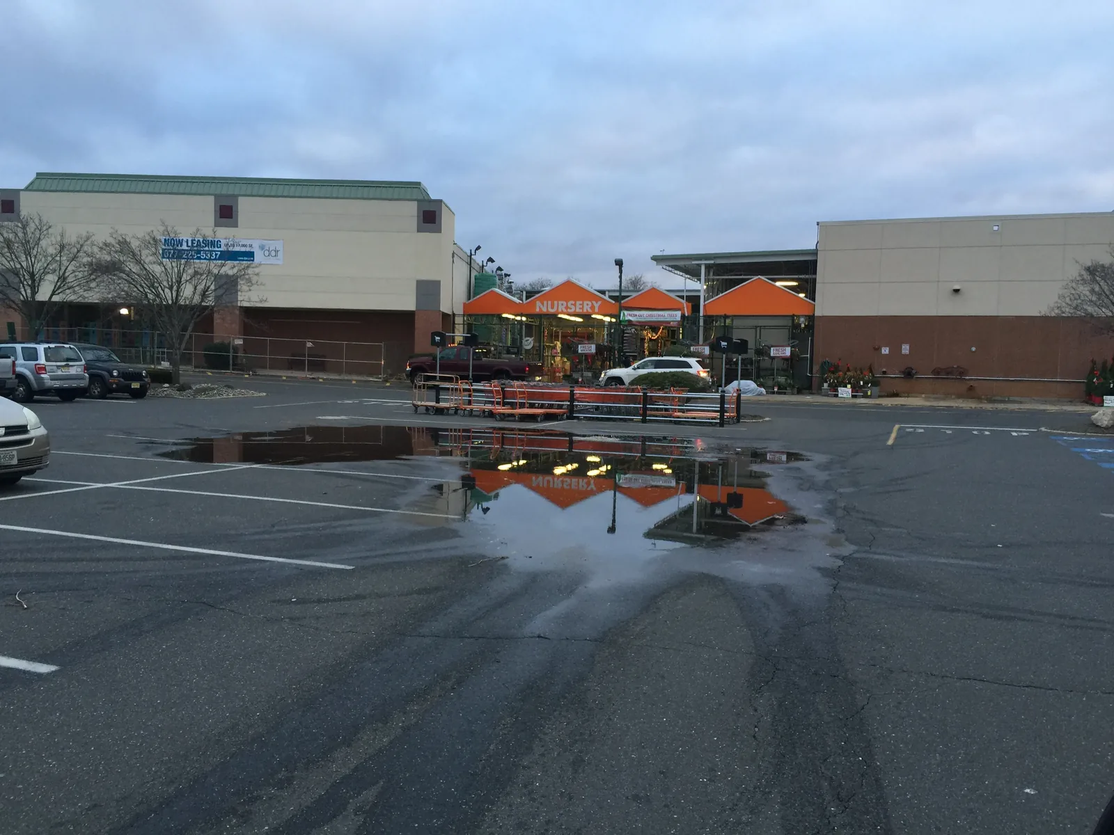 Large area of standing water in a commercial parking lot after rain