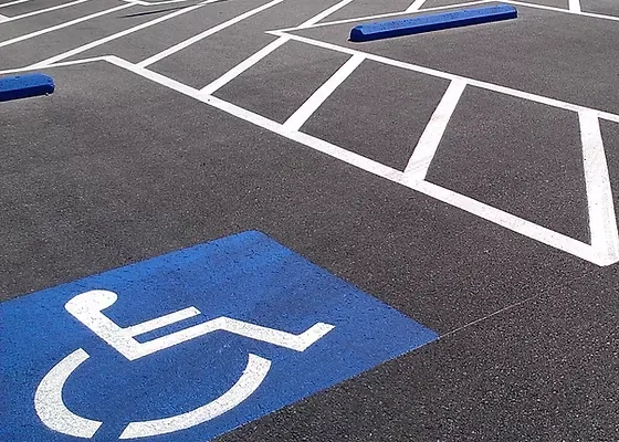 Accessible parking symbol and striped access aisle markings on asphalt