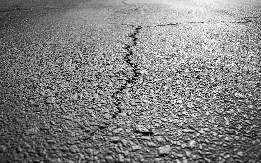 Parking lot pavement assessment showing asphalt cracking near a drive aisle