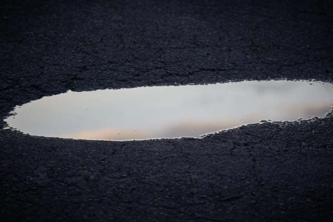 Standing water in a parking lot drainage low spot after rain
