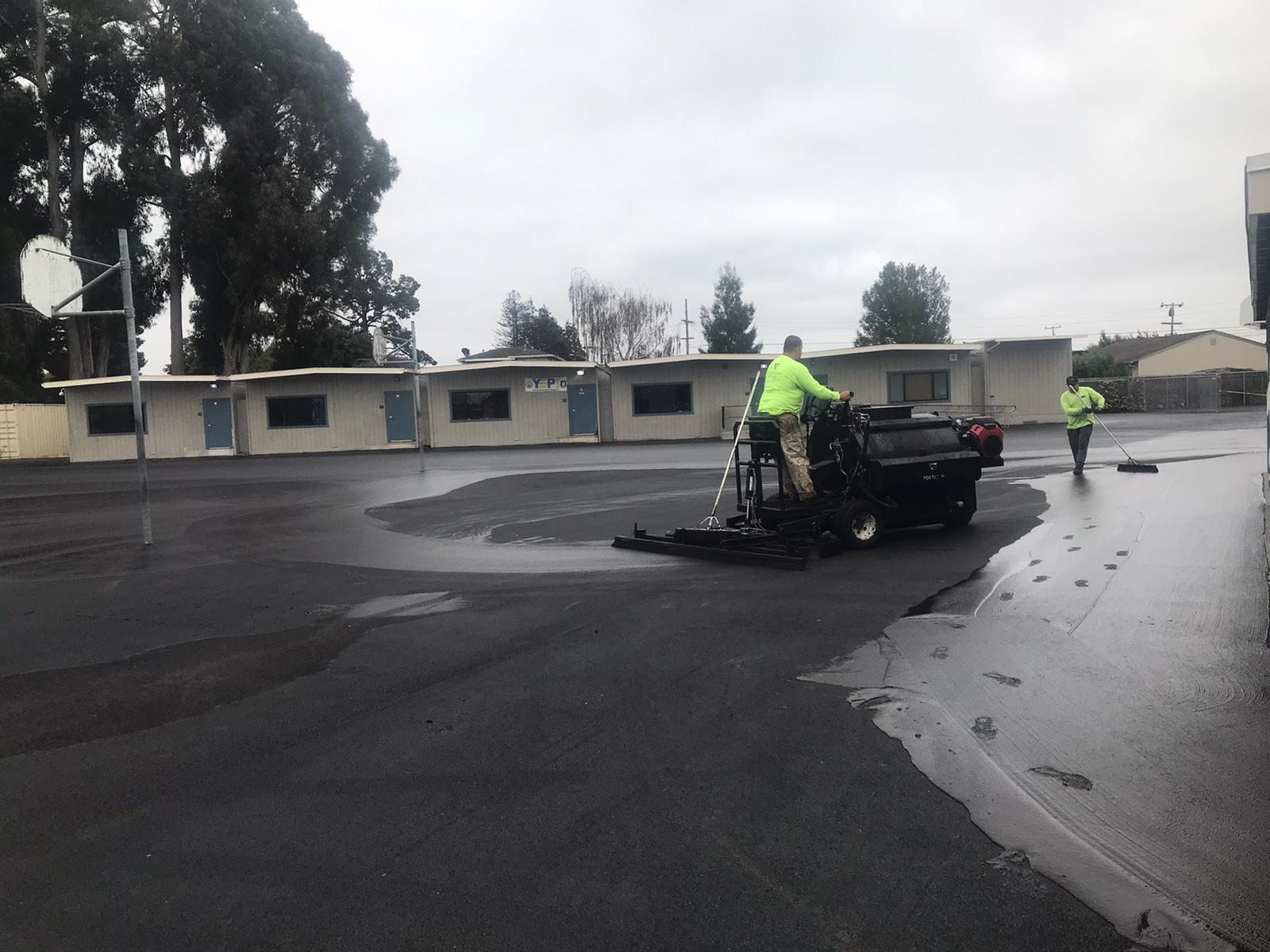 Crew applying sealcoat to a commercial parking lot