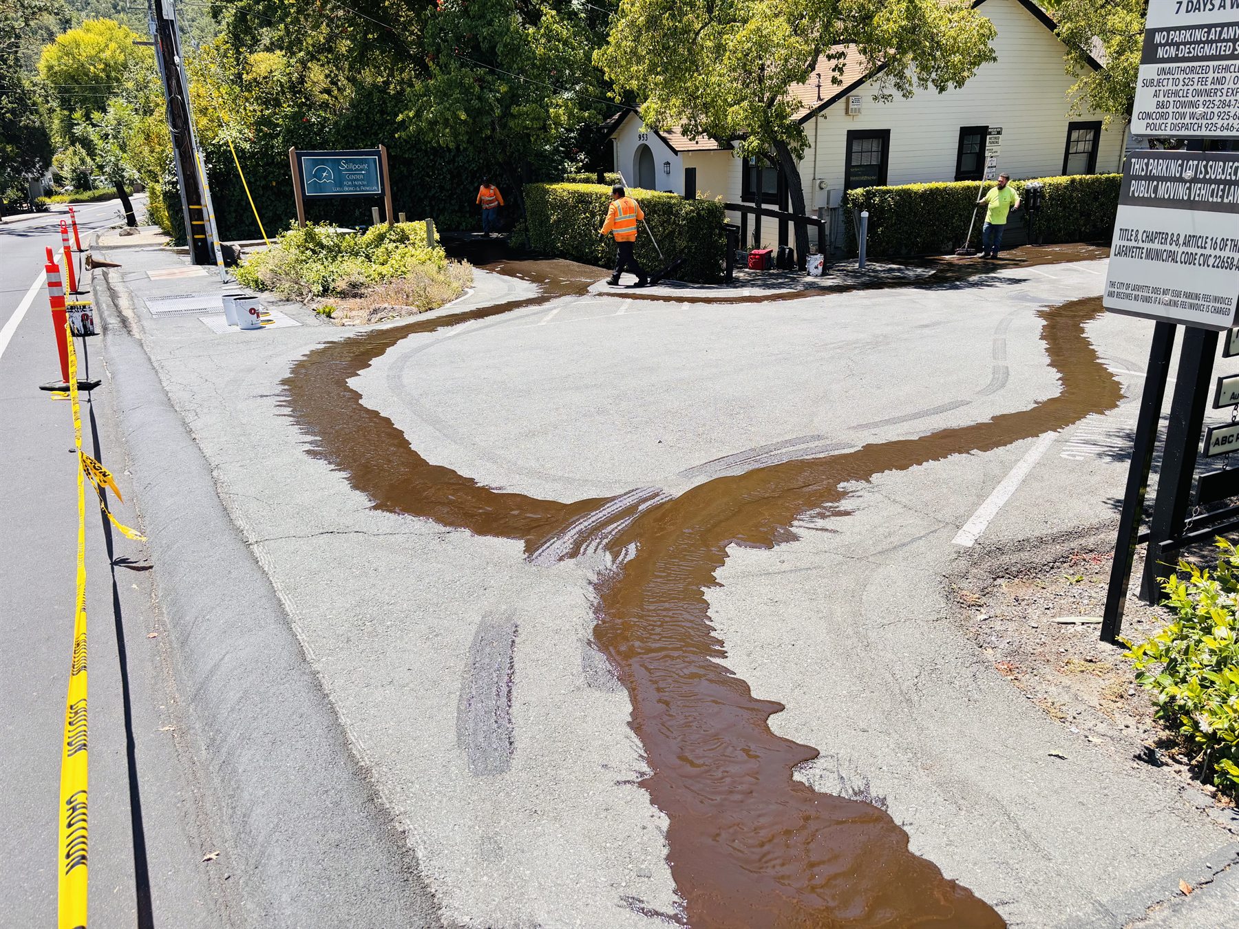 Sealcoat being applied along the edge of an active commercial property
